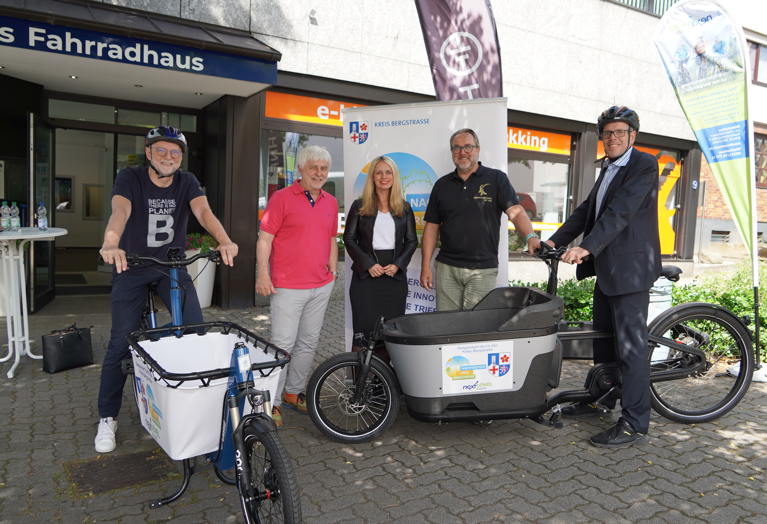 Landrat Christian Engelhardt, Tord Steinbock von Odenwaldbike Lorsch, Corinna Simeth (Leiterin der Abteilung Grundsatz und Kreisentwicklung beim Kreis Bergstraße), Wolfgang Bund vom Fahrradhaus Bensheim und Klimaschutzmanager Reiner Pfuhl (Kreis Bergstraße) stehen mit zwei Lastenrädern vor dem Geschäft von Odenwaldbike Lorsch.