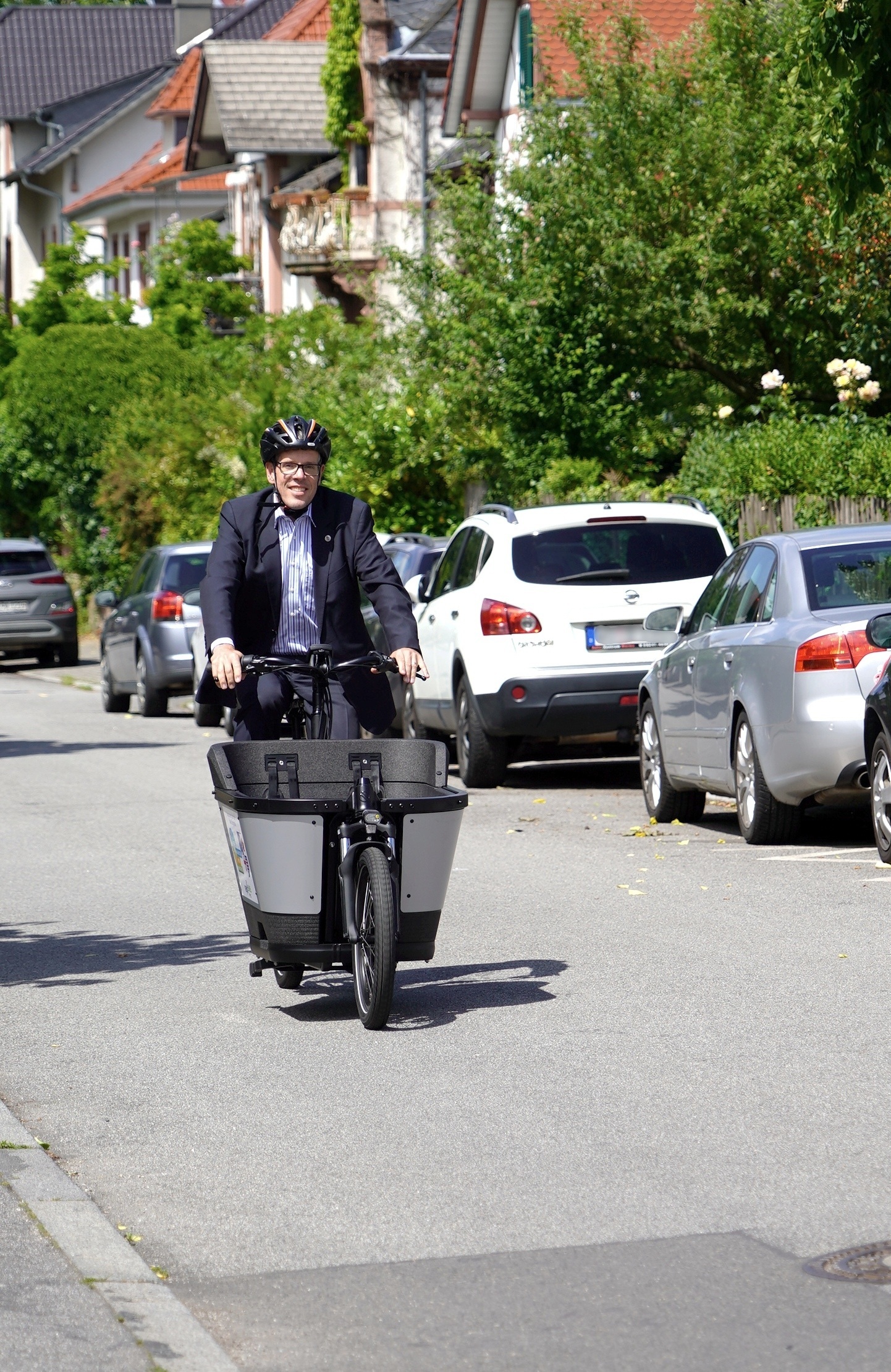 Landrat Christian Engelhardt sitzt auf einem Lastenrad und fährt durch eine Straße in Bensheim.