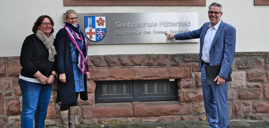 Landrat Christian Engelhardt, die kommissarische Schulleiterin, Frauke Böhm, und ihre kommissarische Stellvertreterin, Antje Lohrbach, stehen vor dem denkmalgeschützten Gebäude der Seehofschule in Lampertheim-Hüttenfeld.