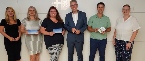 Landrat Christian Engelhardt (3.v.re.) überreicht den drei Gewinnerinnen und Gewinnern Dr. Sandra Thullner, Katharina Becker, Oliver Jägle (v.l.n.r., mit den Gutscheinen in der Hand) im Rahmen der Bergsträßer Bildungsumfrage ihre Segelflug-Gutscheine. Mit dabei: Corinna Simeth, Leiterin der Abteilung Grundsatz und Kreisentwicklung beim Kreis (ganz links) sowie Barbara Meyer, Sachbearbeiterin im Fachbereich Bildung der Kreisverwaltung (ganz rechts).