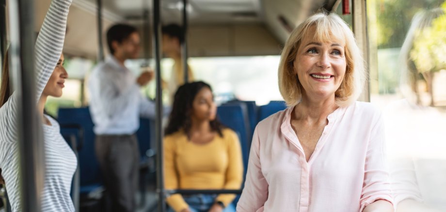 Eine ältere Frau fährt stehend in einem Bus.