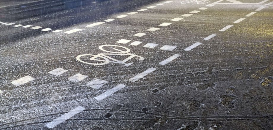Schneematsch mit Fußspuren im Winter auf dem Radweg gegen Abend in der Senckenberganlage im Stadtteil Bockenheim am Westend von Frankfurt am Main in Hessen