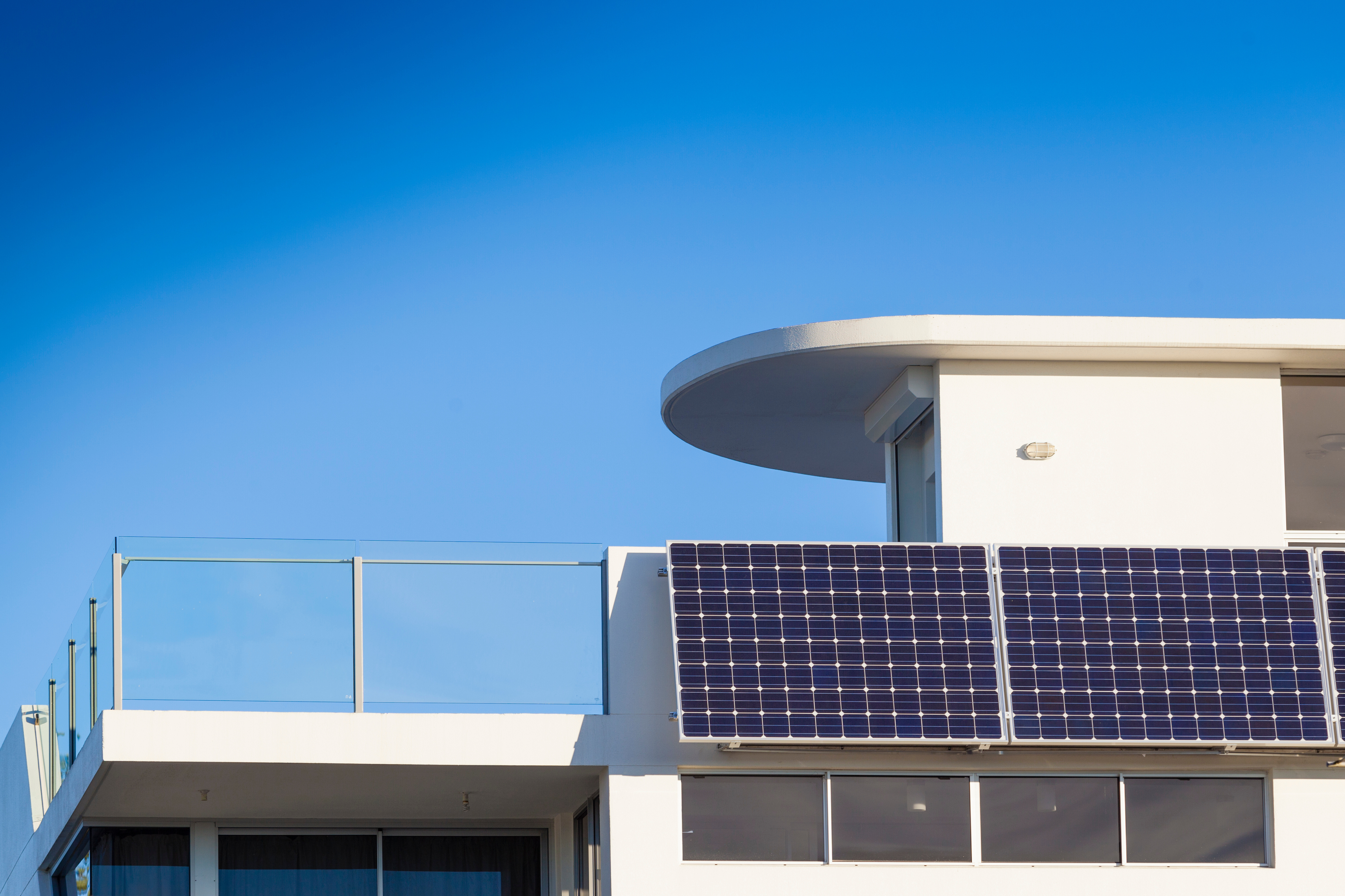 Ein Photovoltaik-Modul ist an einem weißen Hausbalkon angebracht.